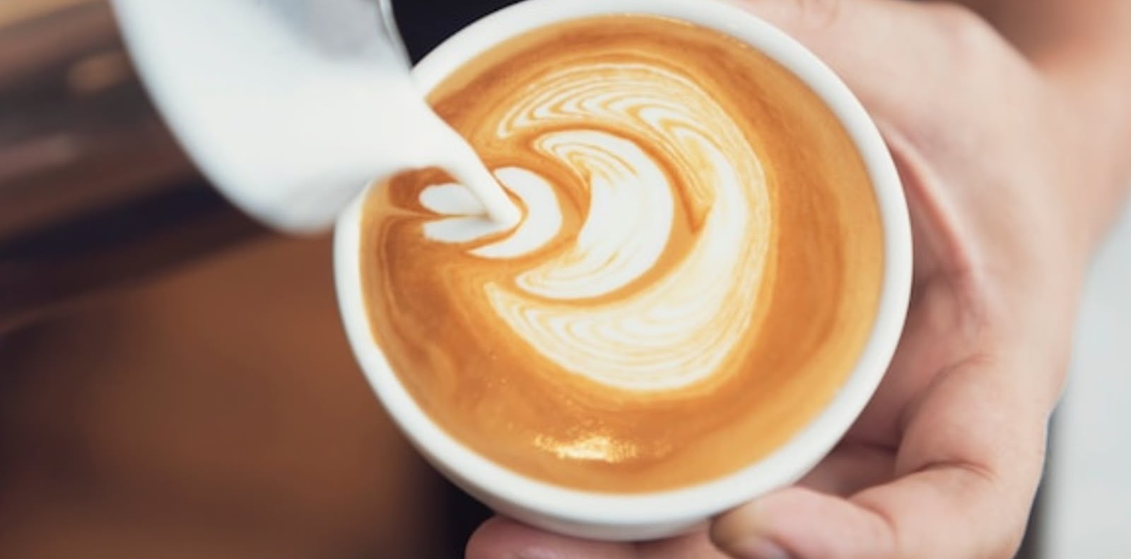 Barista pouring heart latte art at Col's Family Cafe